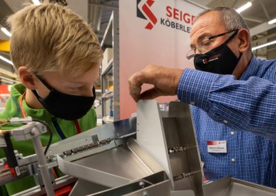 Ein Mitarbeiter von Köberlein & Seigert erklärt einem Jugendlichen im Rahmen der INDUSTRIE INTOUCH die Funktion der Zuführtechnik
