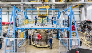 Teammitglieder der N3 Engine Overhaul Services GmbH & Co. KG, einem teilnehmenden Unternehmen bei der INDUSTRIE INTOUCH 2022, montieren eine große Turbine in einer Fertigungshalle.