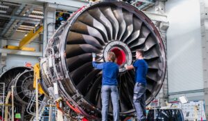 Zwei Teammitglieder der N3 Engine Overhaul Services GmbH & Co. KG, einem teilnehmenden Unternehmen bei der INDUSTRIE INTOUCH 2022, arbeiten in einer Werkhalle an einer großen Turbine.