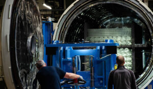 Zwei Teammitglieder der Raesch Quarz (Germany) GmbH, einem teilnehmenden Unternehmen bei der INDUSTRIE INTOUCH 2022, bestücken einen Industrieofen mit Quarzglasrohren.