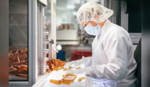 Ein Teammitglied der Röchling Medical Solutions SE, einem teilnehmenden Unternehmen bei der INDUSTRIE INTOUCH 2022, führt eine Sichtprüfung von neuen PET Rundflaschen durch.